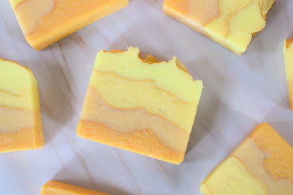 Yellow and orange marbled soap bars on a white marble surface