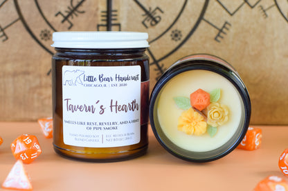 Jar of 'Tavern's Hearth' candle with decorative elements on a wooden surface.